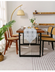 Detail of a Nordic striped table runner with tassel on a minimalist wooden dining table