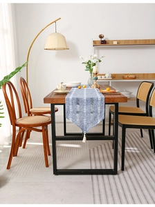 Detail of blue and white hand-woven cotton linen table runner with fringes on wooden table