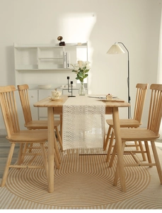 Detailed close-up of cream lace table runner with hollow geometric patterns and tassels