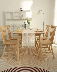 Close-up of bohemian ivory lace table runner with fringe tassels on a wooden dining table
