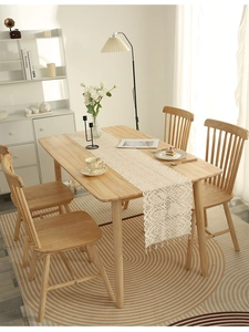 Close-up of cream crochet lace table runner with geometric floral texture and tassels