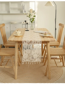 Detailed macro view of white lace table runner with hollow floral pattern and fringe edge