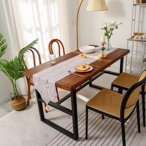 Modern striped table runner with geometric patterns and tassels on a dark wood table