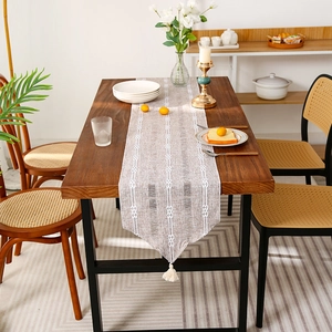 Modern striped table runner with white fringe tassels on a minimalist wooden dining table