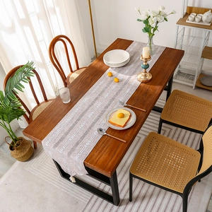 Modern light grey striped table runner with white geometric woven patterns on wood table