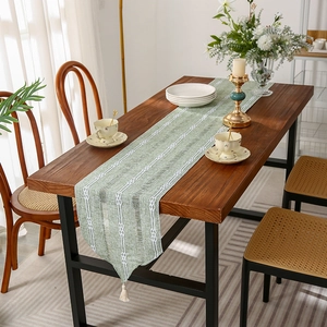 Solid color woven table runner with white geometric patterns and tassel details