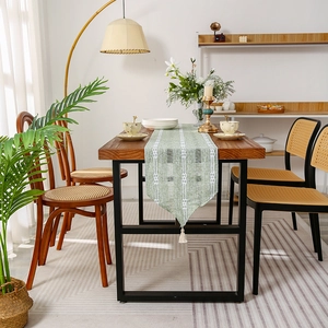 Solid color woven table runner in light green with white wavy stripes and tassels