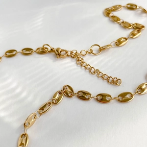 Minimalist golden pig nose mariner link necklace with lobster clasp on water wave background