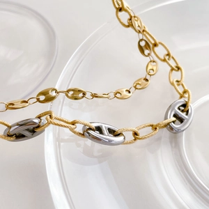 Macro shot of bi-color gold woven chain and silver pig nose link necklace detail