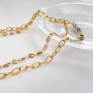 Detailed close-up of mixed gold and silver link chain with spiral and pig nose motifs