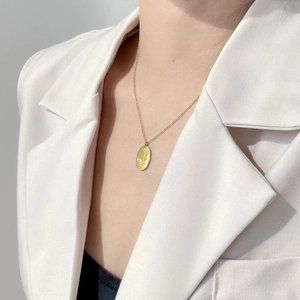 Détail d'un pendentif ovale doré avec gravure florale sur un collier en or