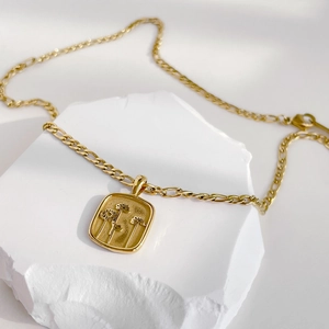 Détail du pendentif tournesol doré sur pierre blanche avec chaîne Figaro classique