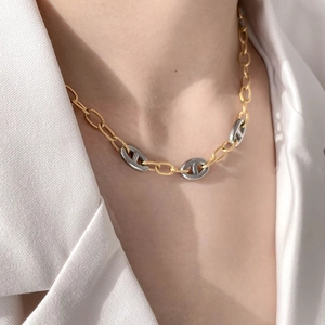 Detail of mixed-metal anchor chain necklace worn with a white silk shirt for women