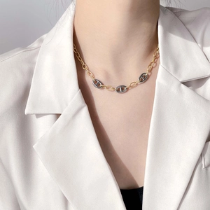 Close-up of mixed-metal pig nose link chain necklace worn on a model with white suit