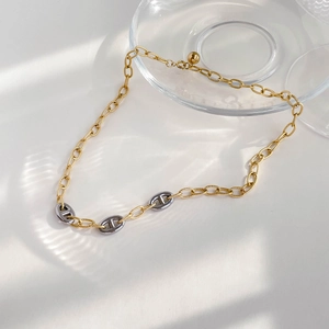 Detail of mixed-metal pig nose anchor chain necklace with subtle light and shadow
