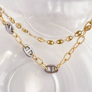 Macro shot of bicolor gold and silver pig nose anchor link necklaces with brushed texture