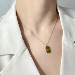 Gros plan d'un collier doré avec pendentif ovale Carnation de janvier sur blazer blanc