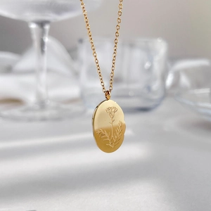 Collier doré élégant avec pendentif ovale et gravure florale sur une chaîne fine