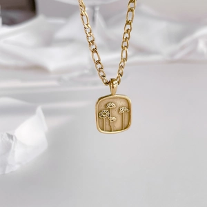 Vue macro détaillée du pendentif fleuri doré avec sa chaîne Figaro élégante