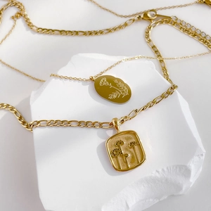 Colliers dorés avec pendentifs marguerite gravés sur un socle en pierre blanche