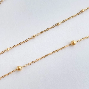Makroaufnahme einer minimalistischen Goldperlenkette mit polierten Kugelelementen