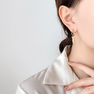 Gros plan de boucles d'oreilles corps féminin artistique en finition or 18 carats