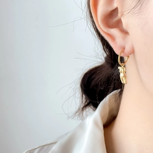 Boucles d'oreilles créoles dorées avec silhouette de corps abstrait et perle sur modèle