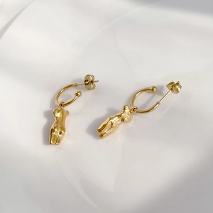 Détail macro de boucles d'oreilles art corporel abstrait en acier plaqué or 18K
