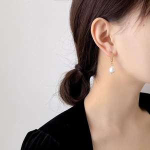 Gros plan de boucles d'oreilles créoles minimalistes en or 18K avec perle sur un mannequin