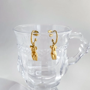 Gros plan de boucles d'oreilles artistiques dorées à l'or 18 carats sur un verre