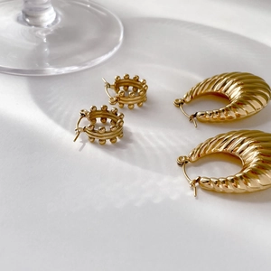 Set of 18K gold beaded hoop and croissant style earrings on white textured surface