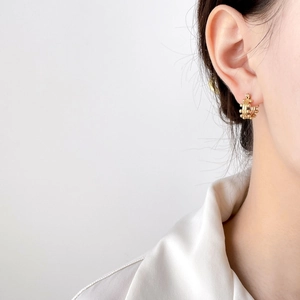 Macro view of gold hoop earrings with beaded texture worn on a model ear
