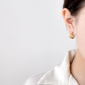 Golden bead-embellished C-shaped hoop earrings worn by a model in a minimalist style