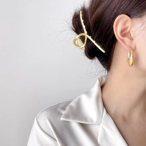 Close-up of elegant gold croissant earrings and matching hair claw on a female model