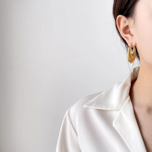 Elegant gold croissant hoop earrings featuring high-gloss spiral texture on model