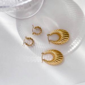 Detail of gold beaded hoops and vintage croissant style earrings on white surface