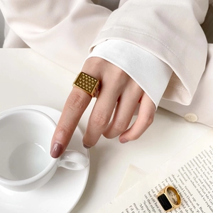 Minimalist gold square signet ring with embossed grid texture on a hand model