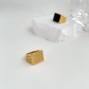 Close-up of vintage gold signet rings with black enamel inlay and geometric grid textures