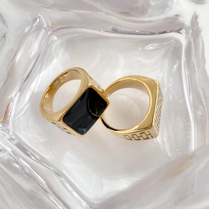 Macro shot of gold square black enamel signet ring and geometric engraved band set