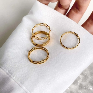 Détail d'un ensemble de quatre bagues chaîne dorées sur un fond de satin blanc soyeux