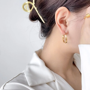 Close-up of a model wearing minimalist golden U-shaped geometric triangle hoop earrings