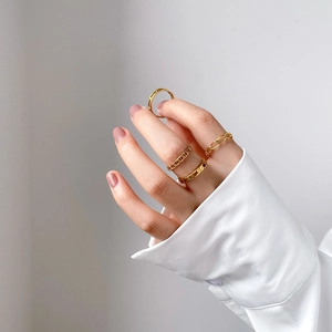 Ensemble de quatre bagues dorées à maillons et style minimaliste portées par un mannequin