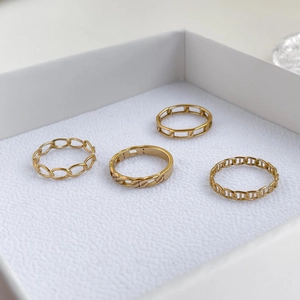 Détail de quatre bagues en maille dorée aux textures géométriques dans un écrin à bijoux