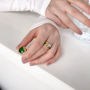 Vintage gold ring set with large emerald cabochon and crystal stones on white background