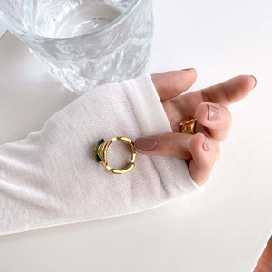 Close-up of a gold ring featuring a deep green emerald stone with minimalist stacking style