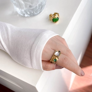Detailed shot of vintage gold ring with large square crystal and green emerald stone