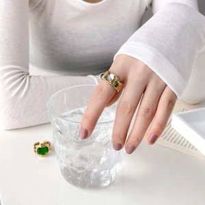 Detail of vintage gold ring with emerald green and clear rectangle gemstones on hand