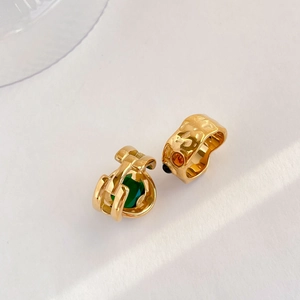 Detail of vintage textured gold earrings with emerald green and amber gemstones