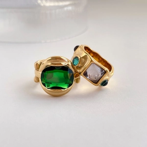 Detail of vintage gold-plated rings featuring a large emerald-cut green stone and lava texture