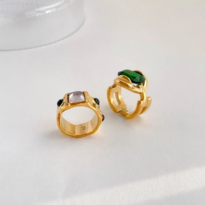 Macro shot of luxury gold-plated rings with emerald green and lavender gemstones